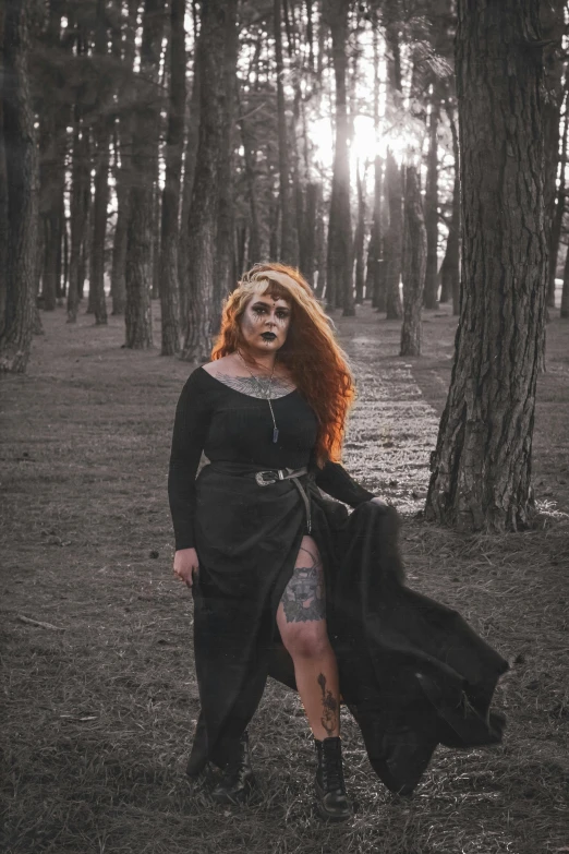 a beautiful redhead woman with tattoos standing in the woods