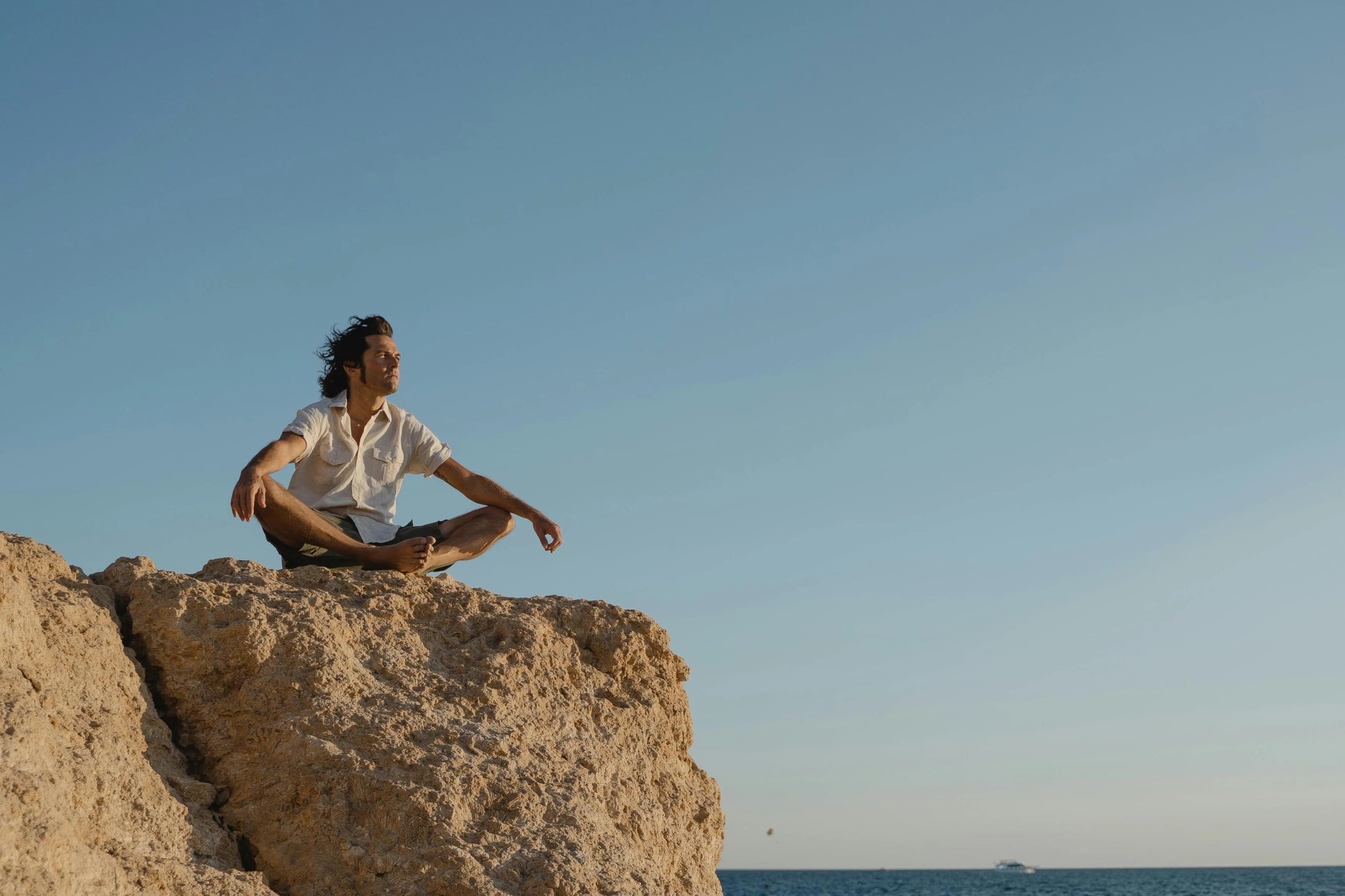 a man sitting on top of a rock next to the ocean