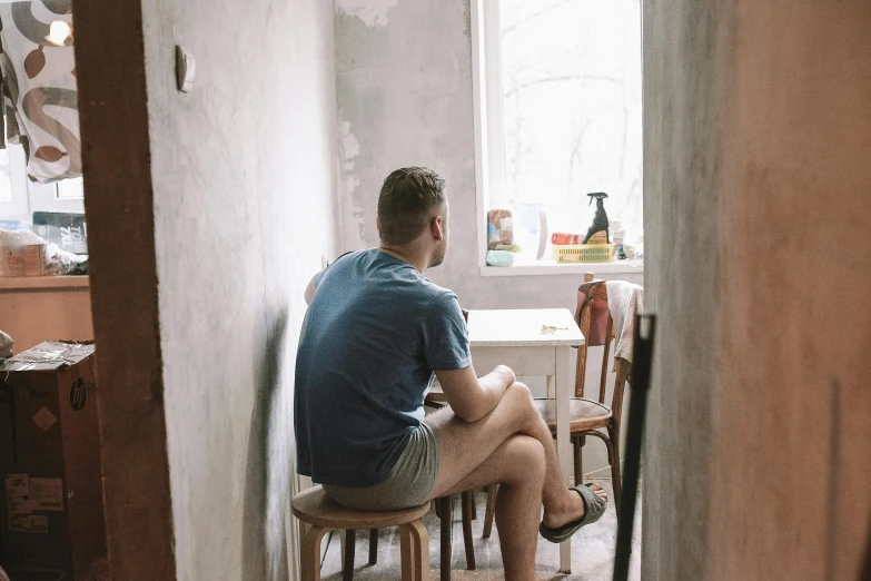 a young man sitting on top of a stool in a kitchen