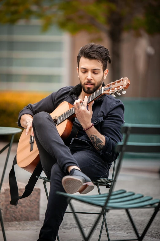 a man with a guitar sitting on a chair outside