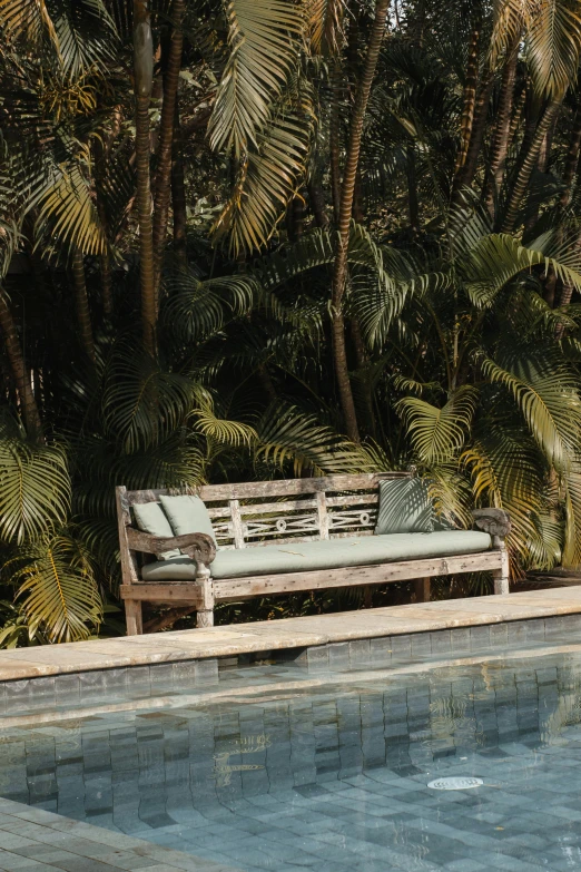 a wooden bench sits next to a large swimming pool