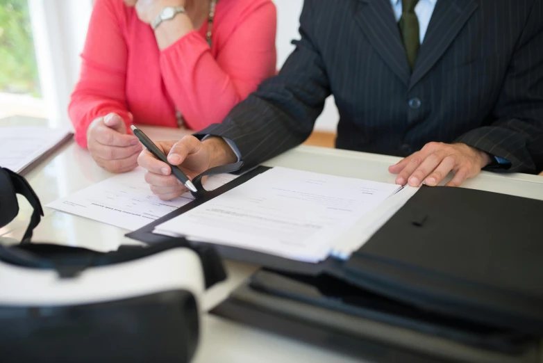 a couple of people sitting at a table with papers