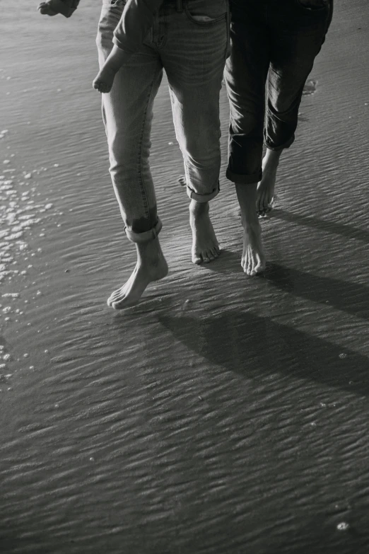 two adults are walking along the sand on a beach