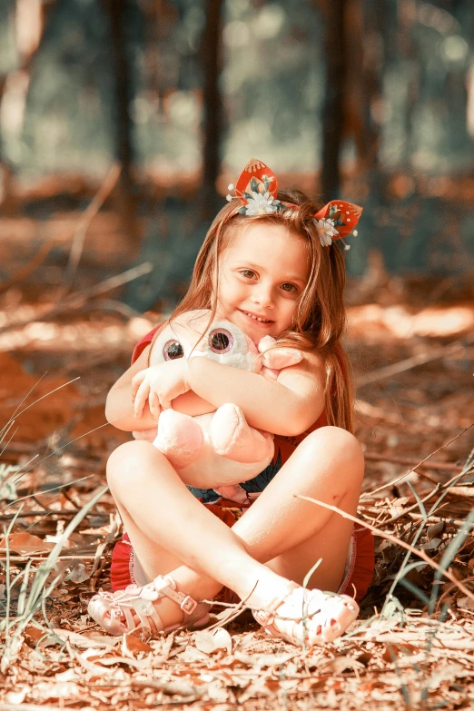 a beautiful  sitting in the woods holding a stuffed toy