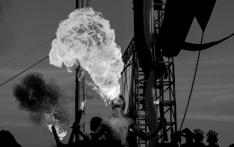 a man standing near a pole that has a large pipe with some fire in it