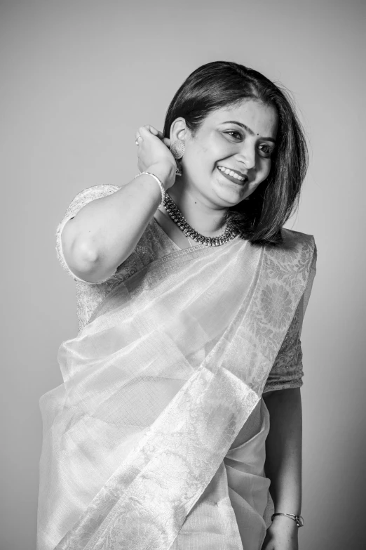 a woman in a blouse smiles with her arm around her head