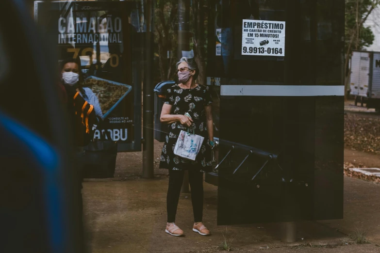 woman holding suitcases waits on the bus stop