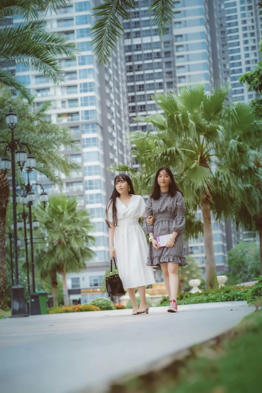 two women in dresses walking on a sidewalk