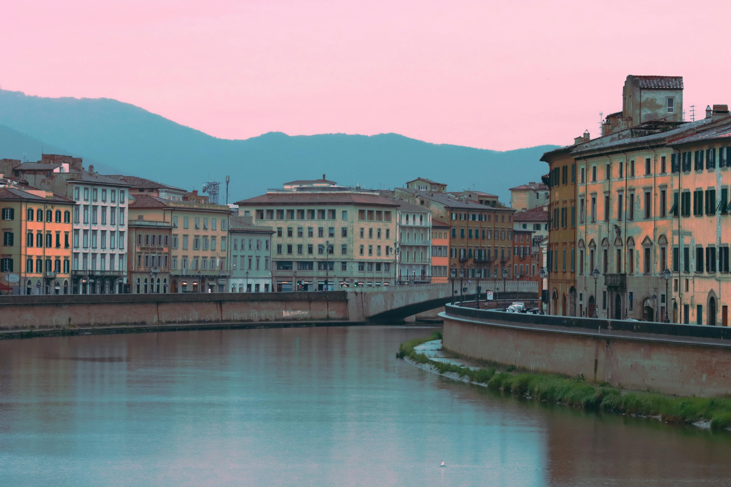 view of various buildings along a river running under a bridge