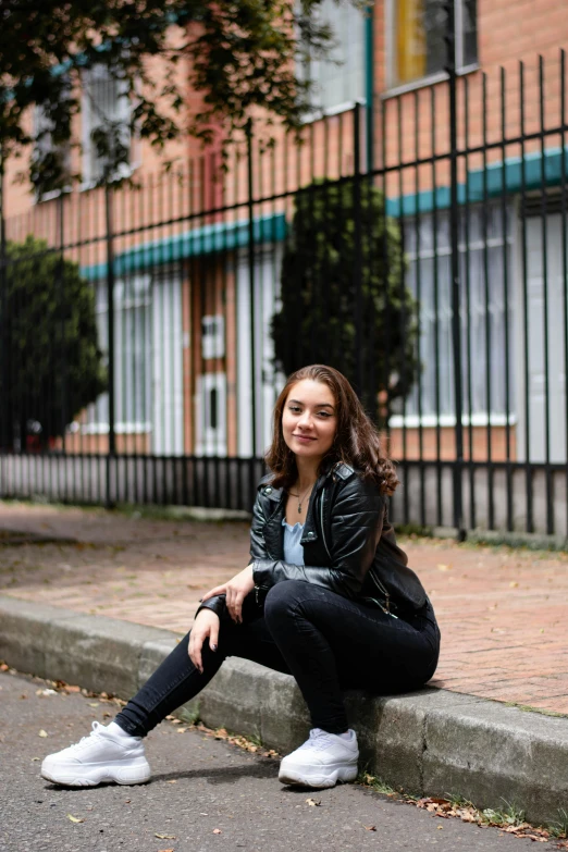 a young woman sitting on a curb, leaning against the corner