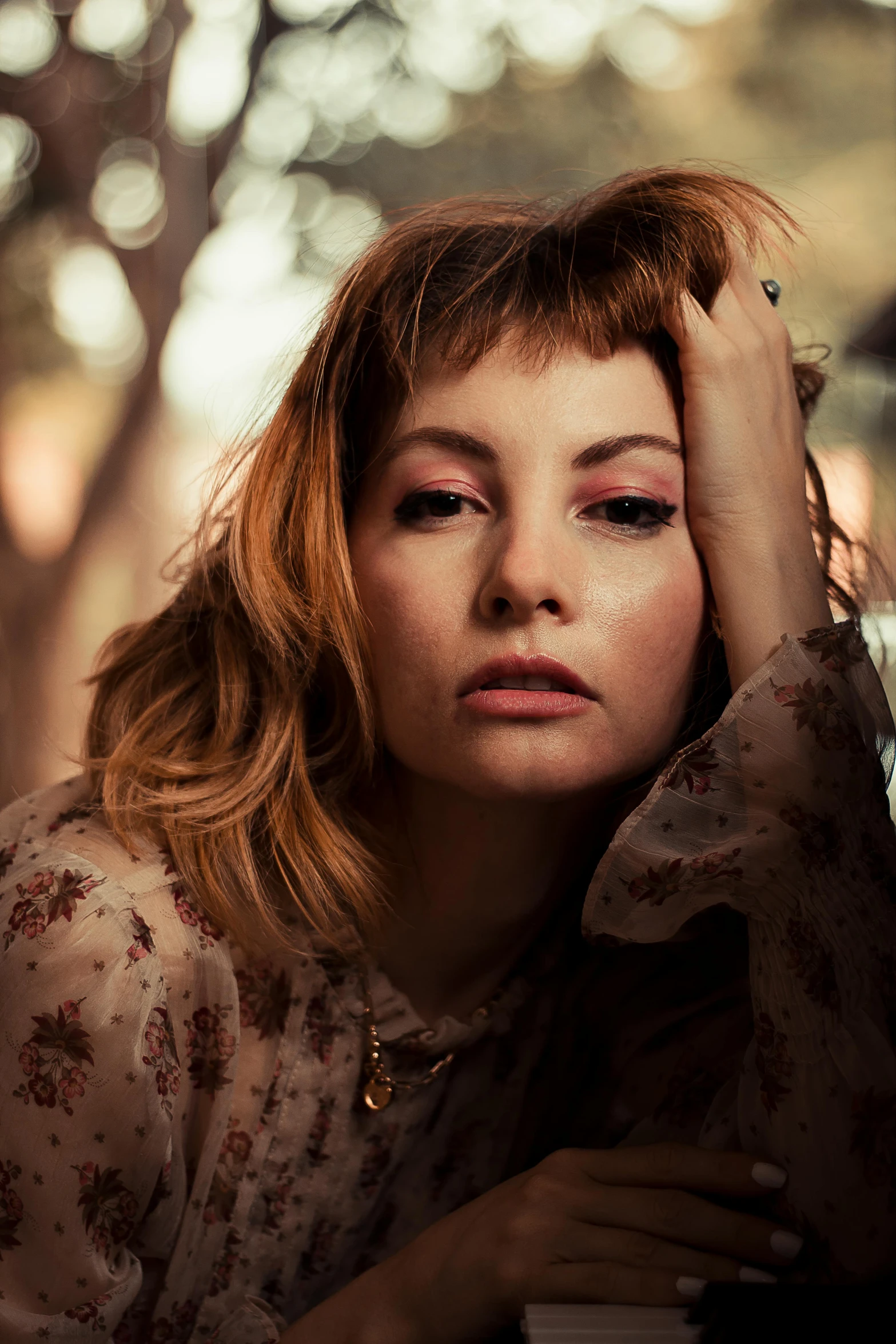 the woman is sitting on a bench holding her hand against her head