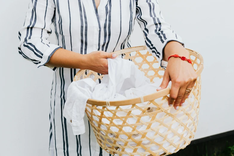 a woman holding a woven basket with clothes inside