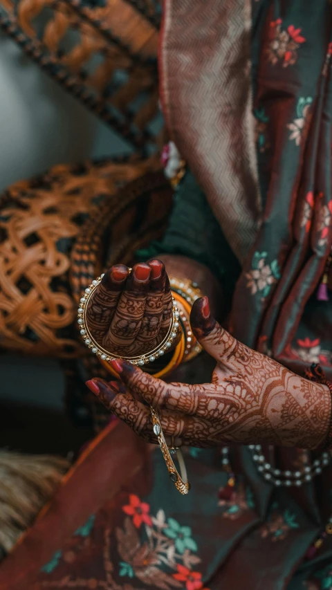 a henna clad woman shows her hands and rings