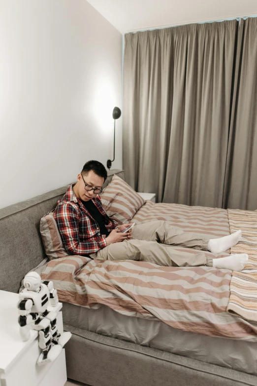 a man on his cell phone sits on a bed