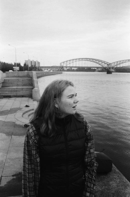 a woman is looking away while standing by the water