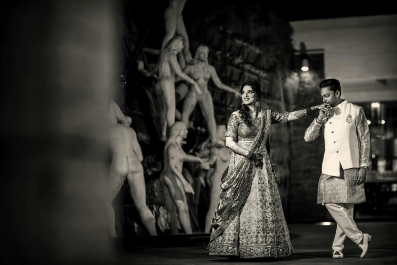 two women dressed in formal attire standing next to a statue