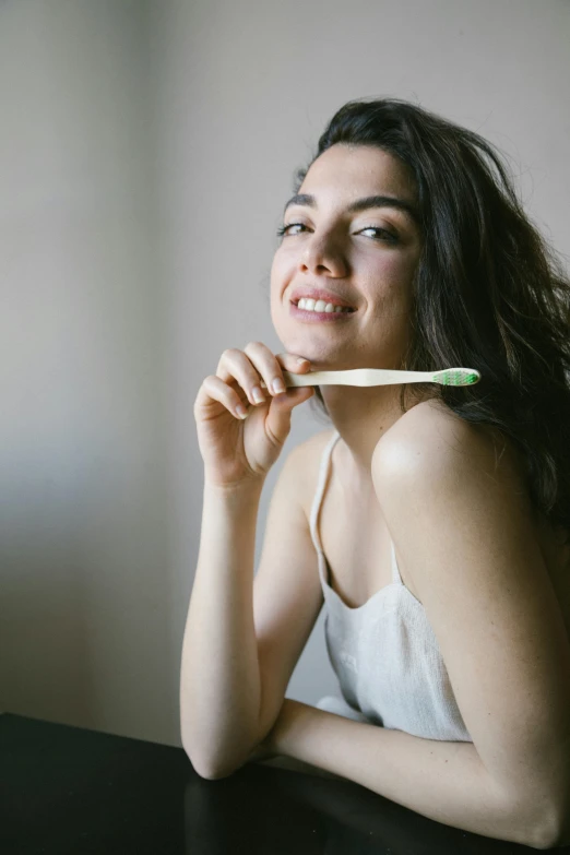 woman sitting in front of a table with a pencil in her mouth