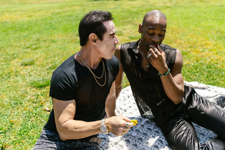 two males sit on the ground one eating