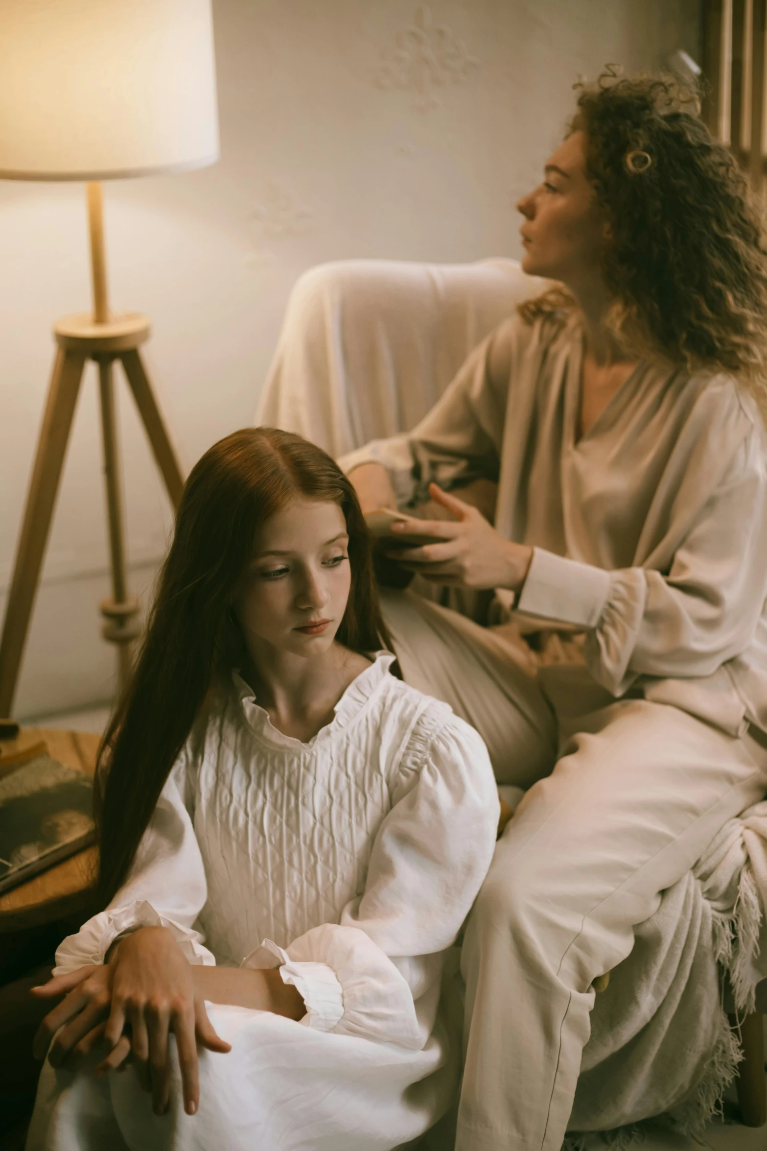 two young women in old clothing sit next to each other