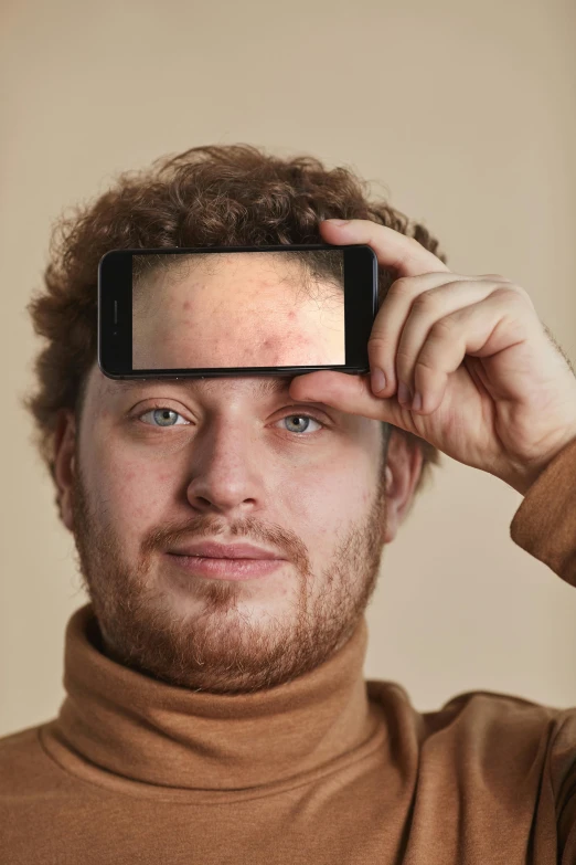 a young man holding up a smart phone to take a po