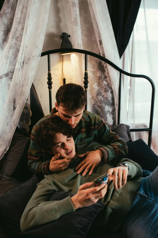 a man and woman lying on a bed with a cell phone