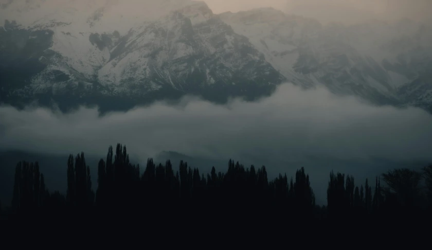 snow capped mountains on the edge of cloudy skies