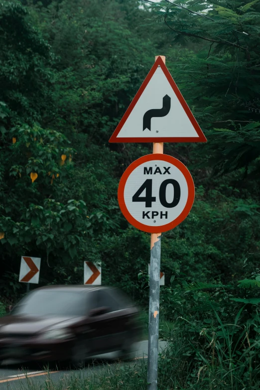 a black car is driving by a sign with a road name