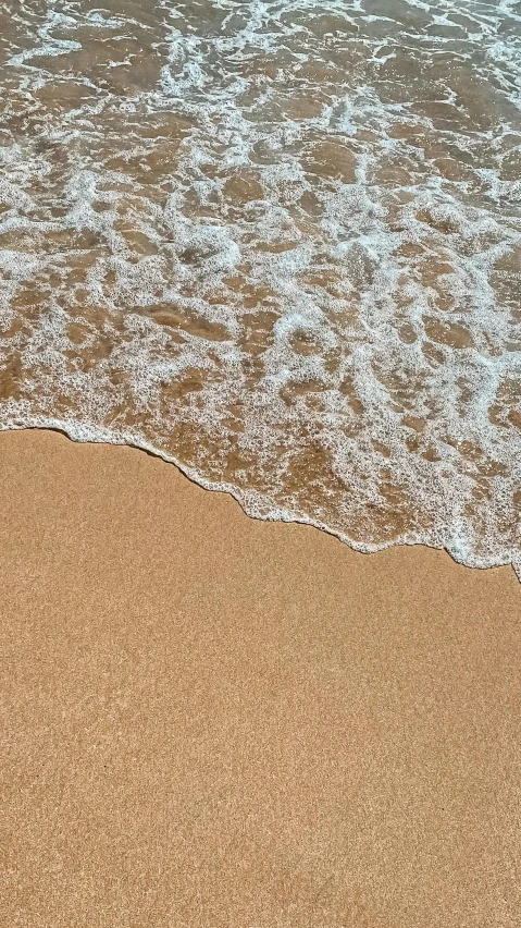 a sandy shore with waves coming in from the ocean
