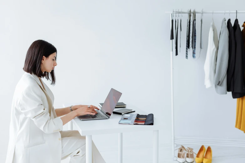 a woman sitting on a white chair using a laptop