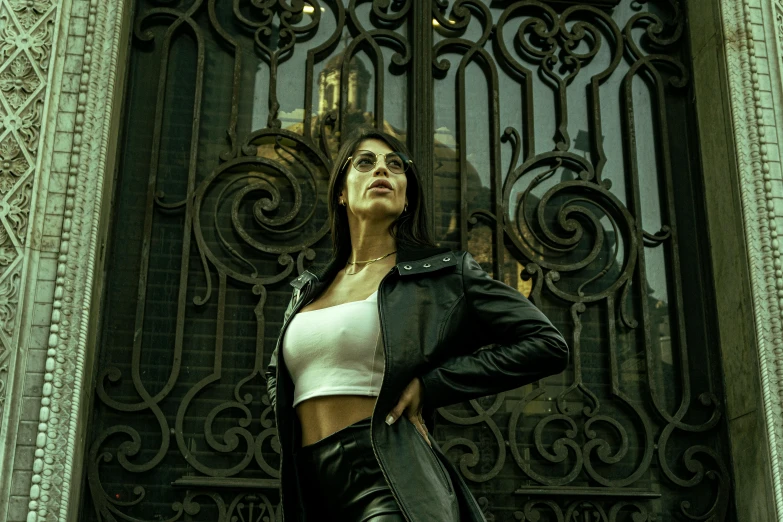 a woman wearing a jacket stands in front of a gate
