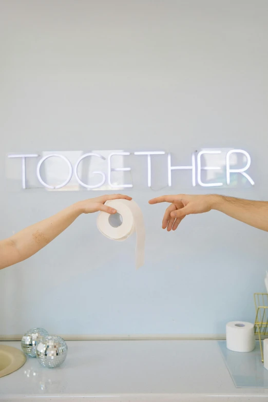 two hands are shown grabbing over a tissue on a table with a sign that reads together
