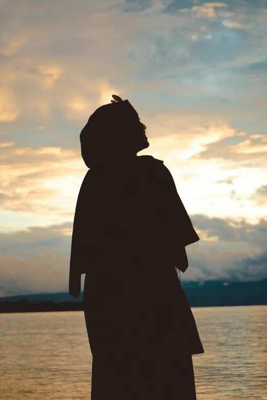 a person is standing near the water on a cloudy day