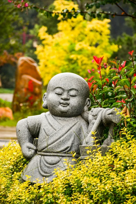 a buddha statue sitting in some yellow flowers