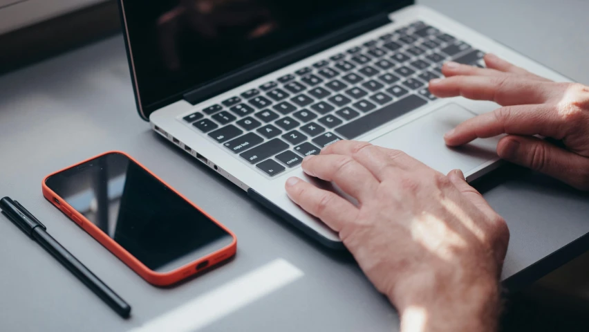 a man uses a laptop and mobile device