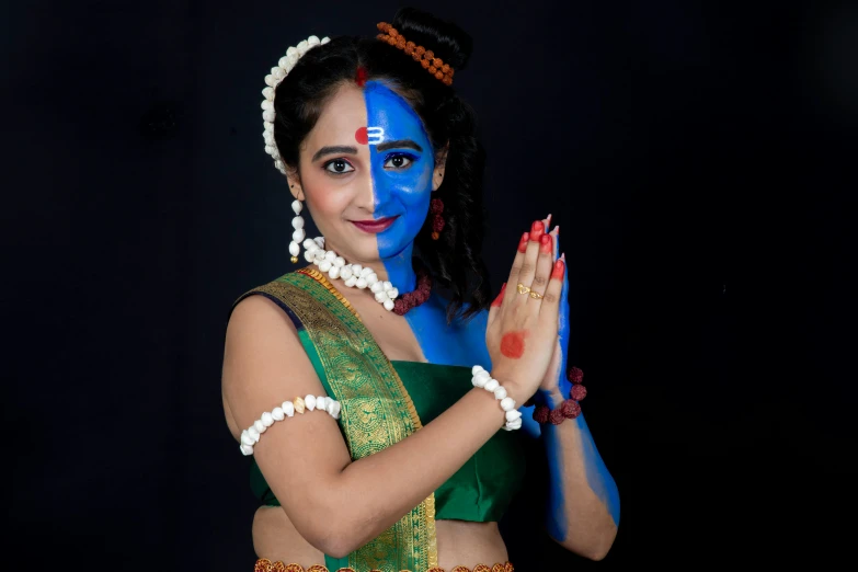 a woman in traditional indian costume in blue with hands together