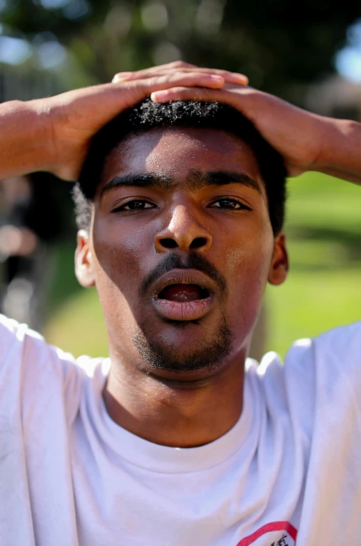 an image of a man in white shirt putting his hair back