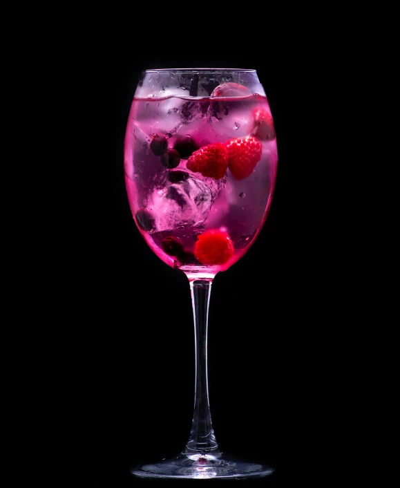 a glass with raspberries in it and ice cubes