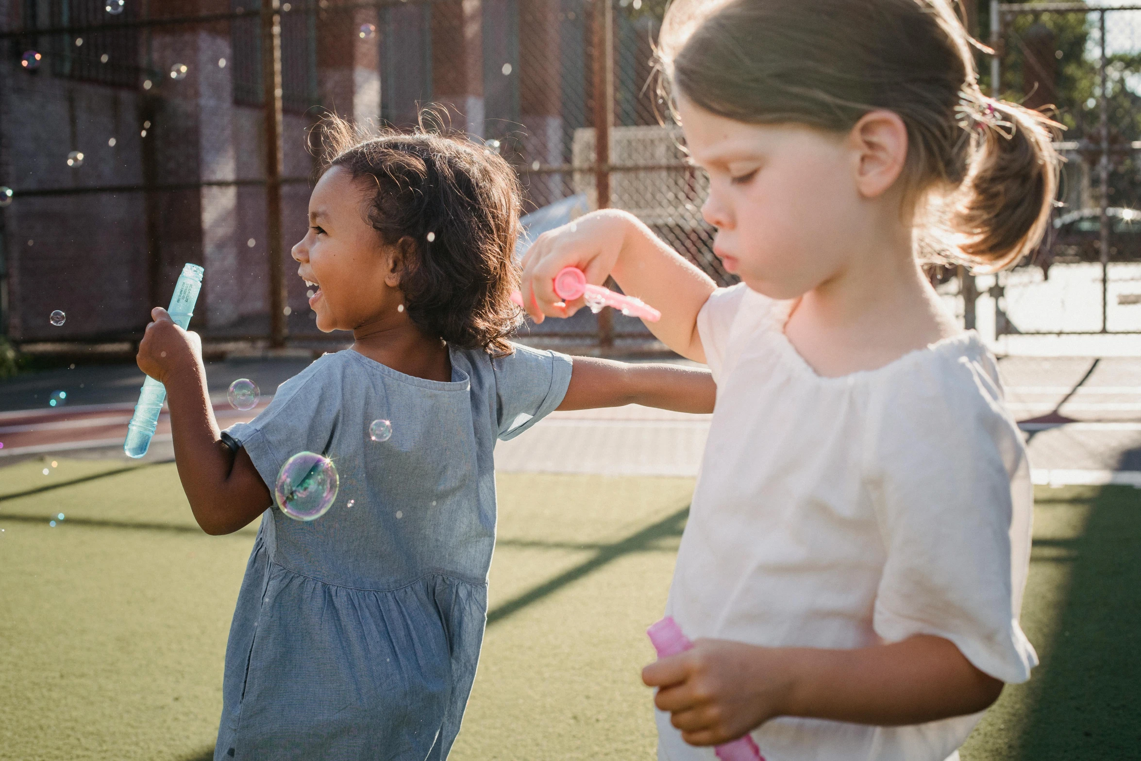 two girls are brushing their teeth outside with bubbles