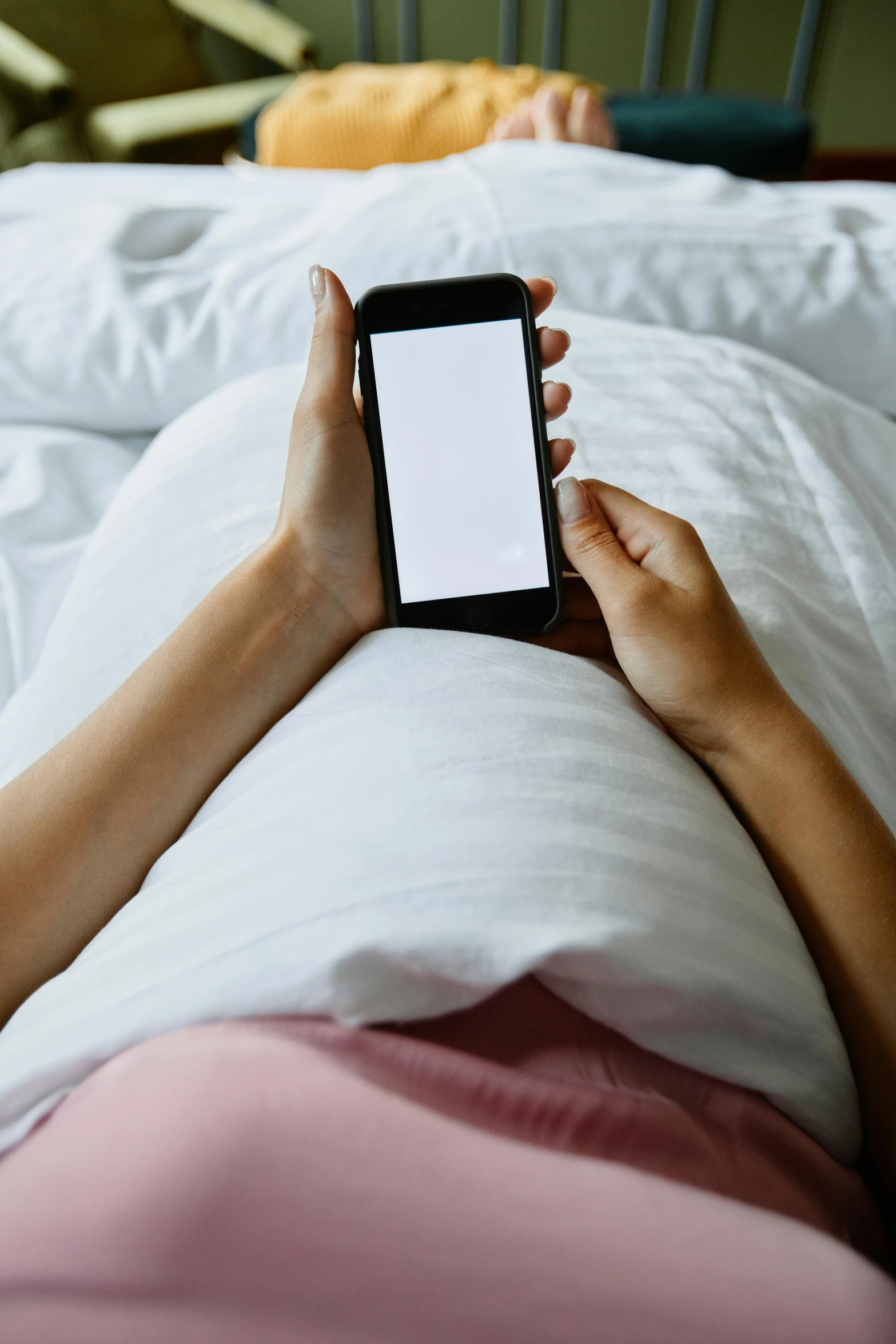 the person is using their phone on top of the bed