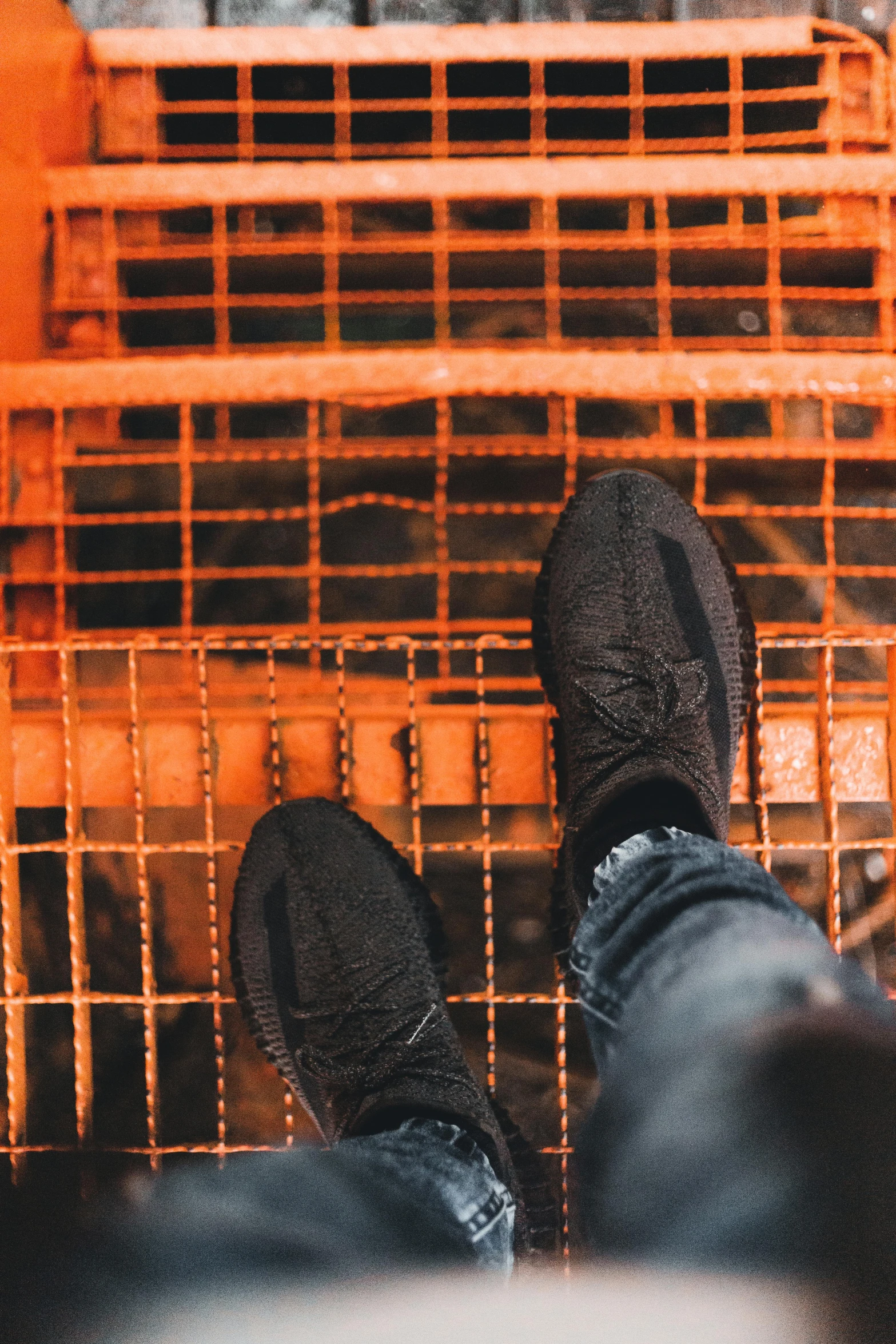 the legs of someone wearing black boots are standing in front of a cage