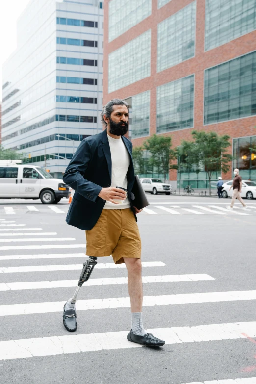 a man walking across a street near tall buildings