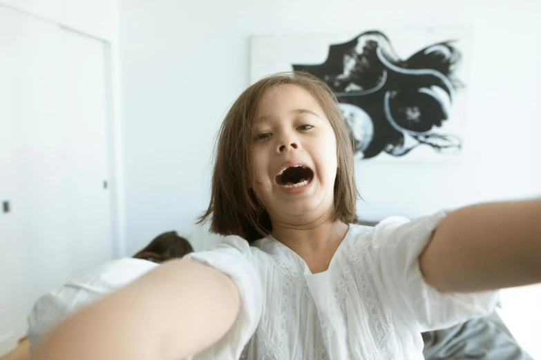 a little girl sitting on top of a bed holding a remote