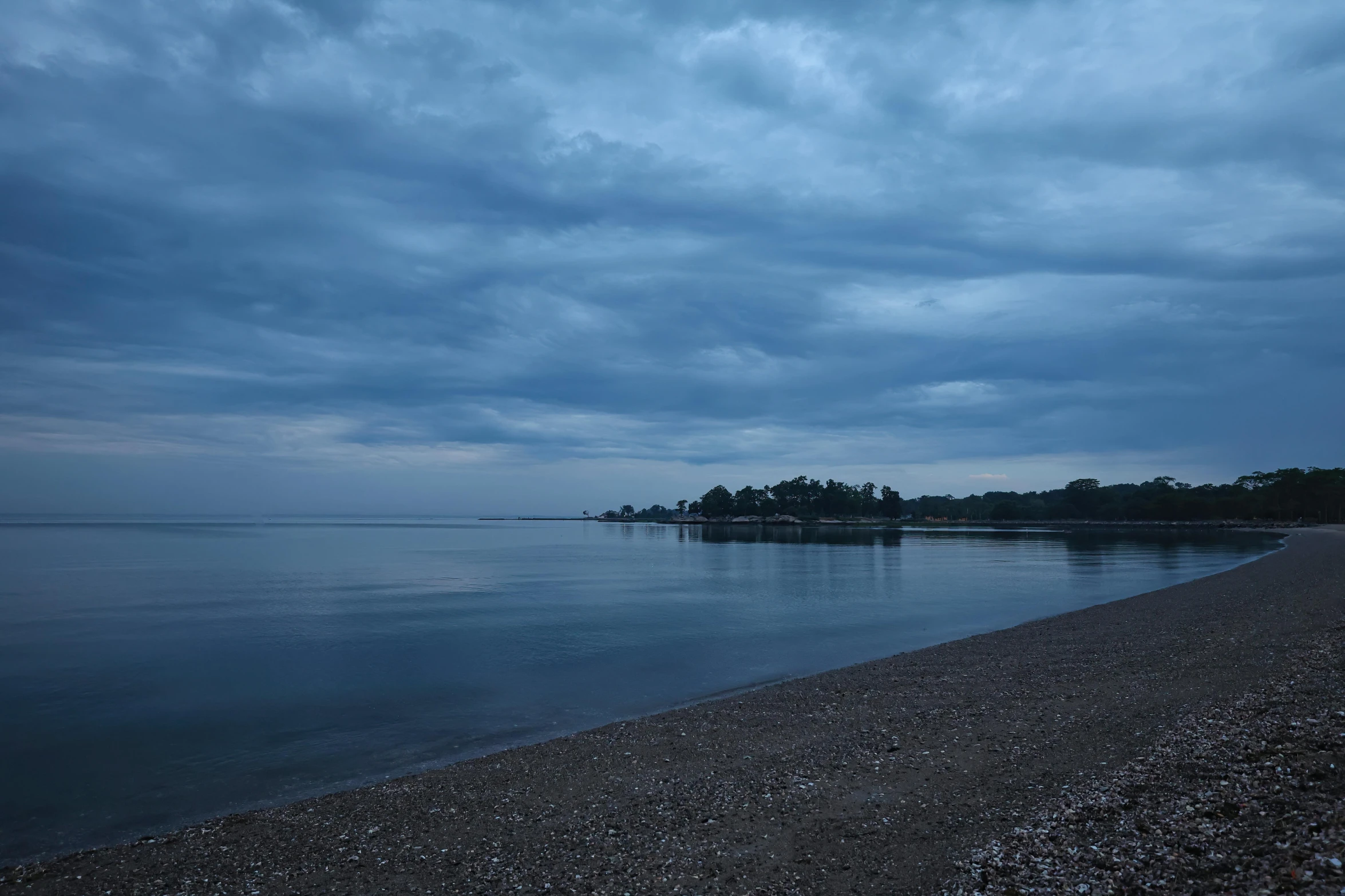 a long stretch of water is shown with trees in the distance