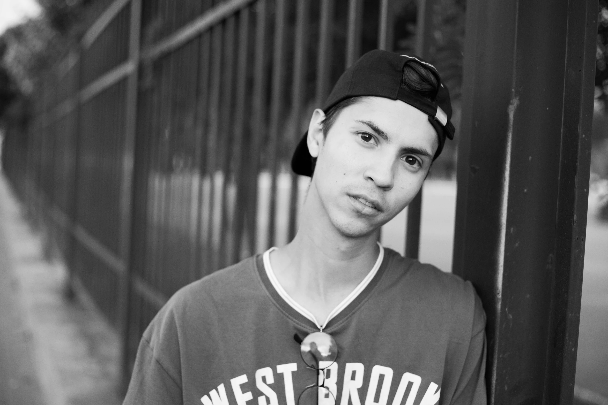 a man standing next to a metal fence wearing a shirt