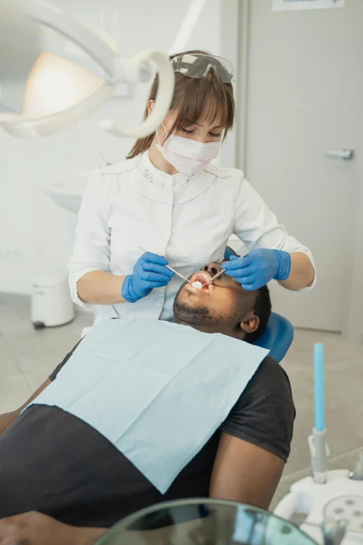 a person with gloves on who is getting his teeth brushed