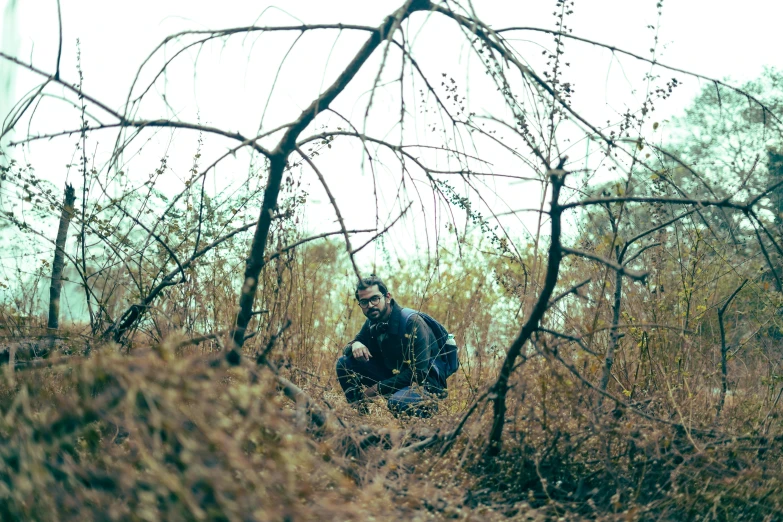 a person crouching in an area with trees