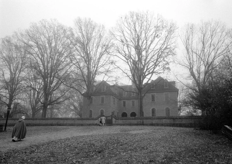 two people walk towards a large mansion sitting on an old country estate