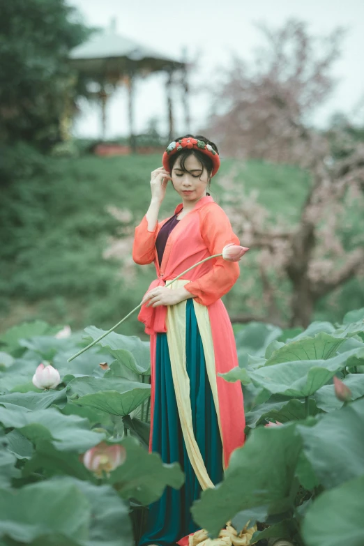 an asian woman in bright kimono standing in a garden