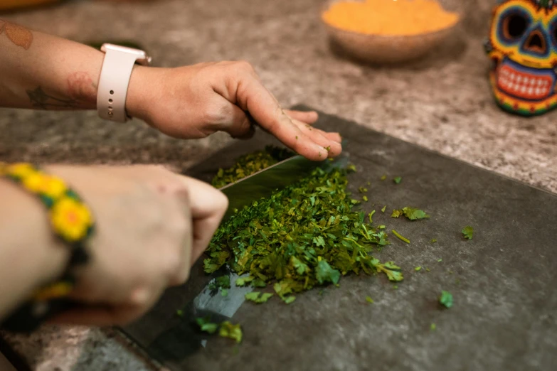 a person is chopping green food with a sharp knife