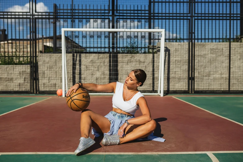 a young woman sitting on the ground with a basketball